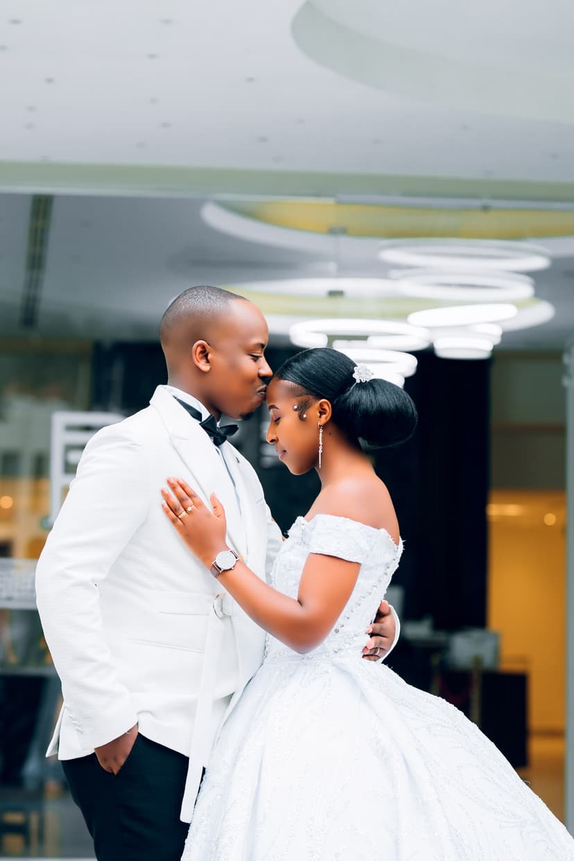 Groom kissing bride on cheek in front of venue