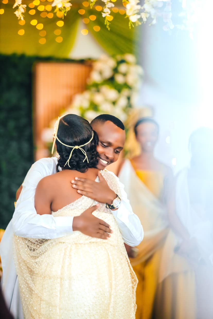 Groom hugging bride at ceremony with golden floral backdrop